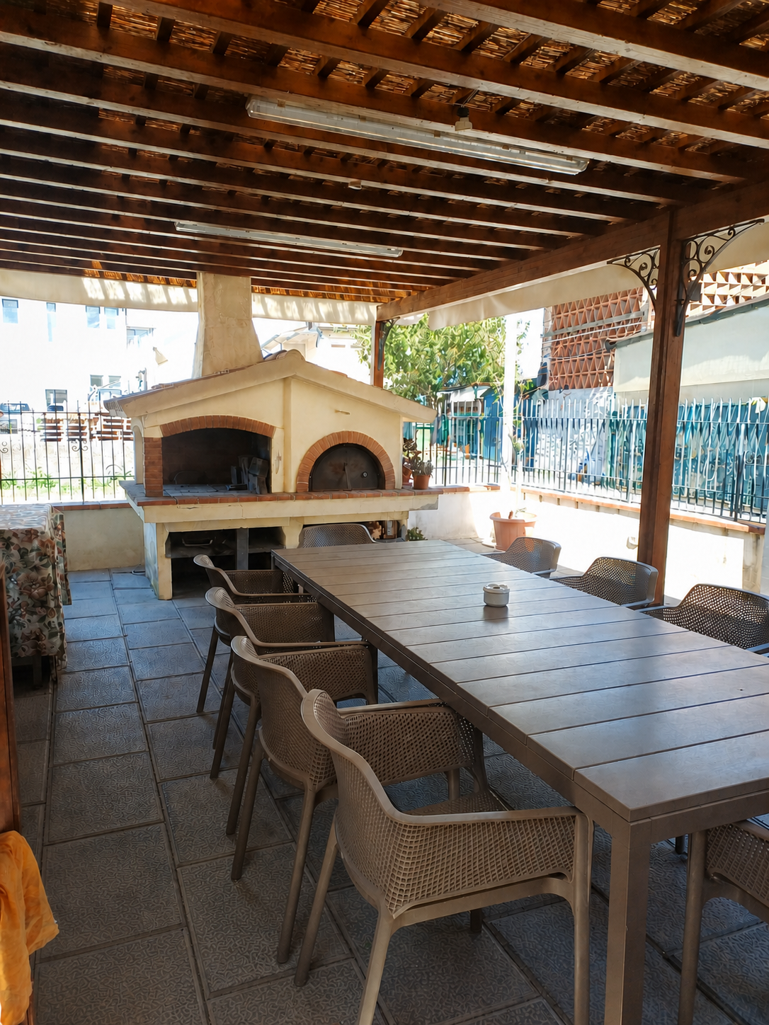 Pergolato coperto con grande tavolo da pranzo e forno a legna