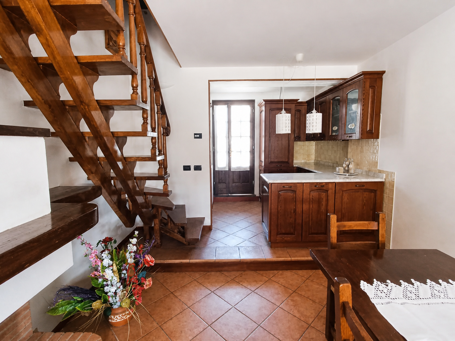 Soggiorno con scala in noce, tavolo da pranzo e cucina